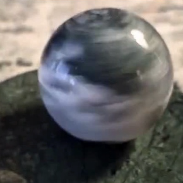 Dark green marbled stone orb outdoors